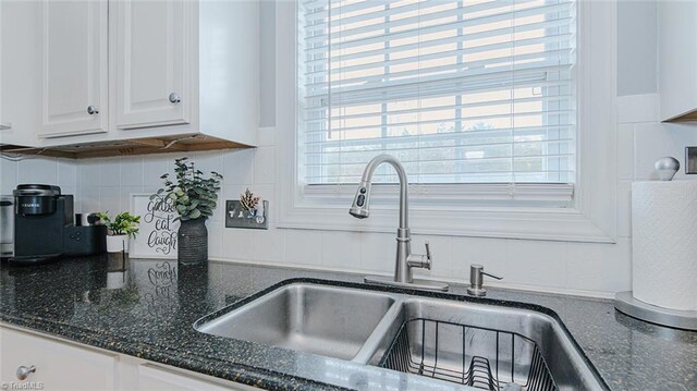 kitchen with tasteful backsplash, sink, white cabinets, and dark stone counters