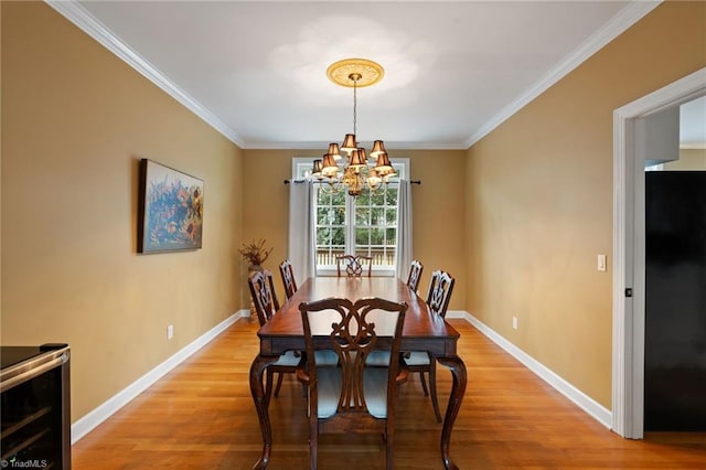 dining area featuring light hardwood / wood-style floors, ornamental molding, and an inviting chandelier