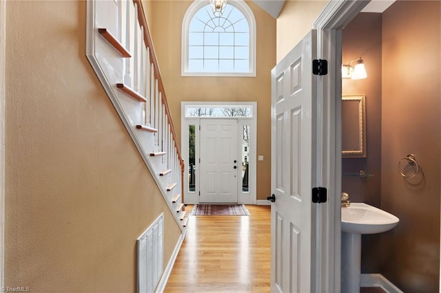 entryway featuring light hardwood / wood-style floors, a towering ceiling, and a healthy amount of sunlight