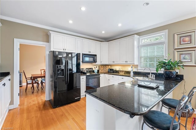 kitchen featuring kitchen peninsula, black appliances, white cabinetry, and dark stone countertops