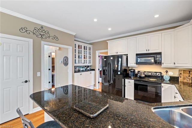 kitchen with black appliances, light wood-type flooring, white cabinetry, and ornamental molding