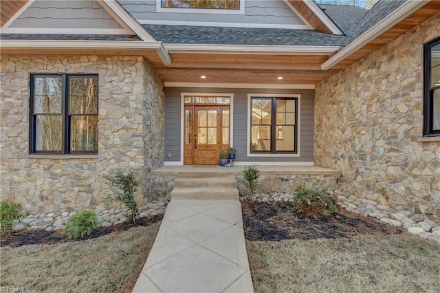 doorway to property featuring a shingled roof, stone siding, and covered porch