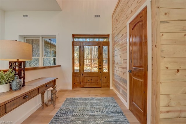 entrance foyer featuring wood walls, visible vents, and light wood-style floors