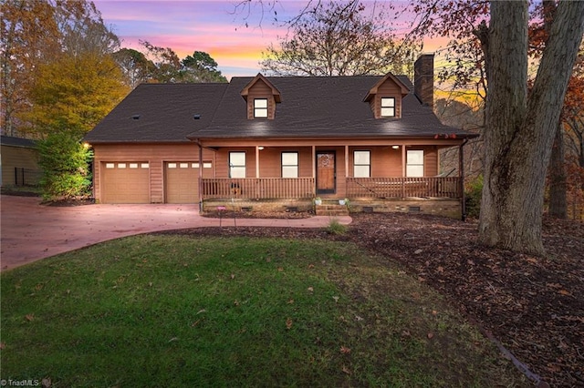 cape cod house featuring covered porch, a yard, and a garage