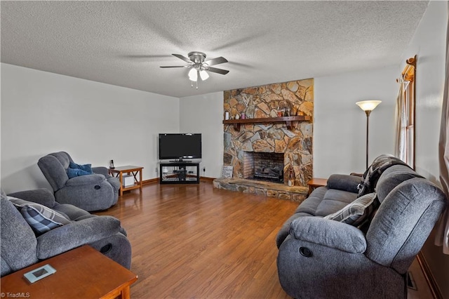 living room with ceiling fan, a fireplace, a textured ceiling, and hardwood / wood-style flooring