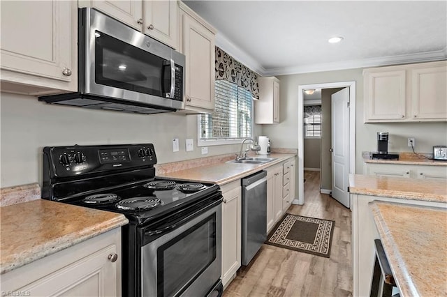 kitchen with white cabinets, sink, ornamental molding, light hardwood / wood-style floors, and stainless steel appliances