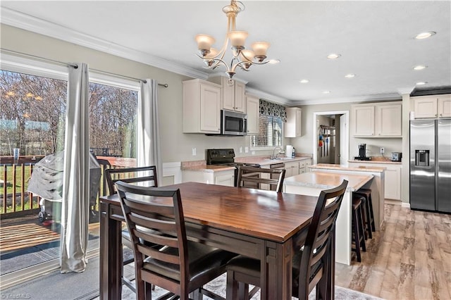 dining space with a notable chandelier, sink, crown molding, and light hardwood / wood-style flooring