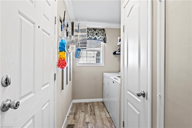 laundry area featuring washing machine and dryer, crown molding, and light hardwood / wood-style flooring