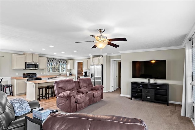 carpeted living room featuring ceiling fan, crown molding, and sink