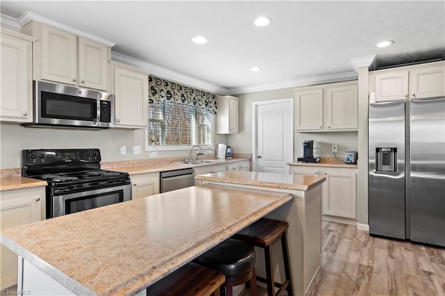 kitchen with a center island, stainless steel appliances, ornamental molding, and light hardwood / wood-style floors