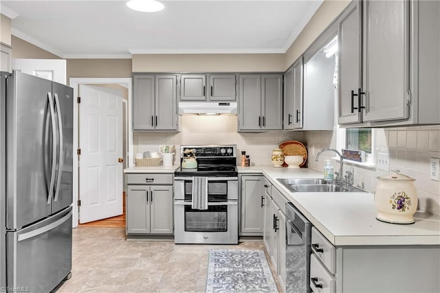 kitchen featuring appliances with stainless steel finishes, gray cabinetry, a sink, under cabinet range hood, and light countertops