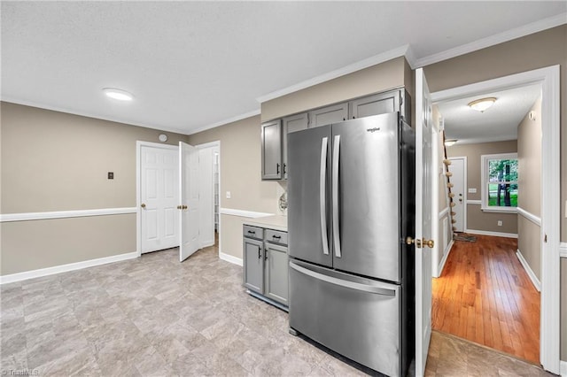 kitchen featuring freestanding refrigerator, gray cabinets, crown molding, light countertops, and baseboards