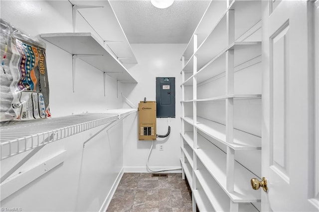 walk in closet with electric panel and stone finish floors