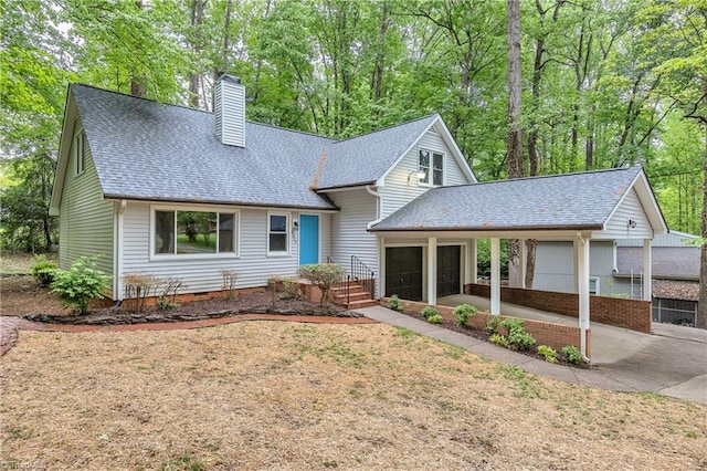 view of front of home with a chimney, roof with shingles, an attached garage, and concrete driveway