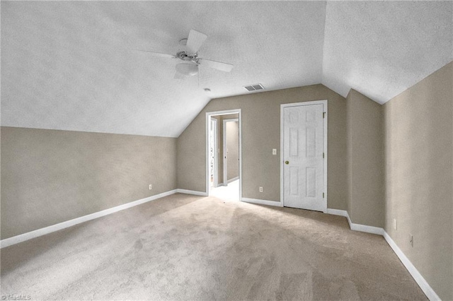 additional living space with vaulted ceiling, ceiling fan, baseboards, carpet floors, and a textured ceiling