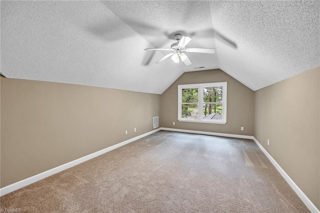 additional living space with a textured ceiling, carpet, vaulted ceiling, baseboards, and a ceiling fan