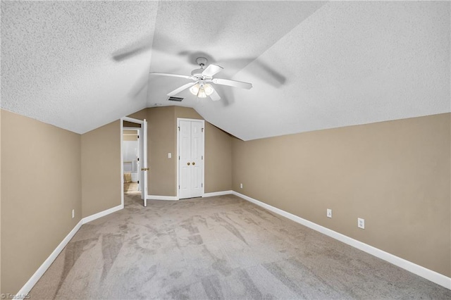 bonus room featuring ceiling fan, a textured ceiling, carpet flooring, baseboards, and vaulted ceiling