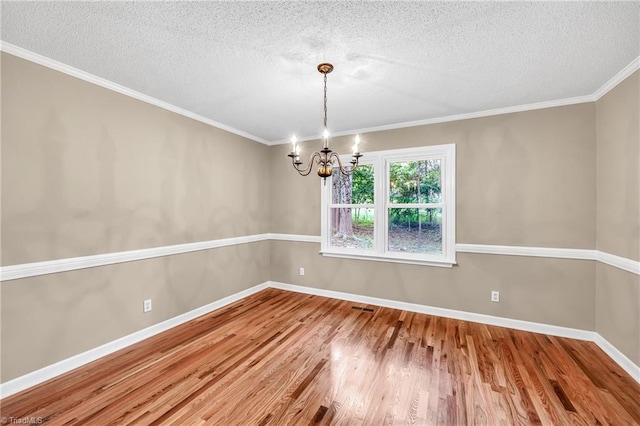 unfurnished room with a textured ceiling, a chandelier, wood finished floors, ornamental molding, and baseboards
