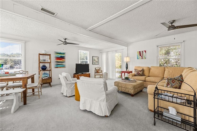 carpeted living room featuring ceiling fan and a textured ceiling