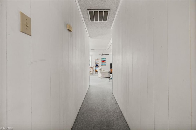 corridor featuring crown molding, wooden walls, and carpet floors