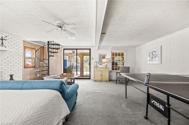 bedroom featuring a textured ceiling, carpet flooring, wooden walls, beamed ceiling, and ceiling fan