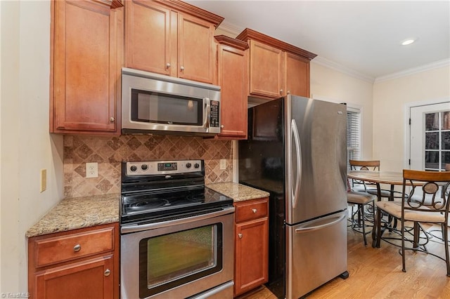 kitchen featuring crown molding, light wood-type flooring, tasteful backsplash, light stone counters, and stainless steel appliances