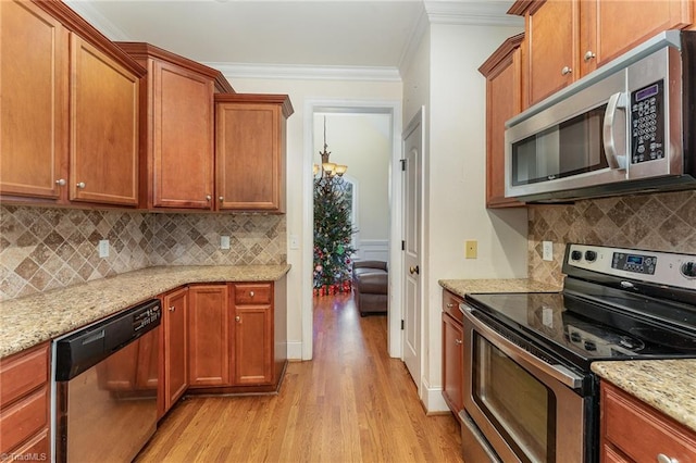 kitchen with tasteful backsplash, stainless steel appliances, crown molding, light hardwood / wood-style flooring, and a notable chandelier