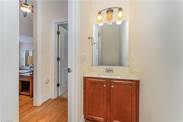 bathroom with ceiling fan, hardwood / wood-style floors, vanity, and crown molding