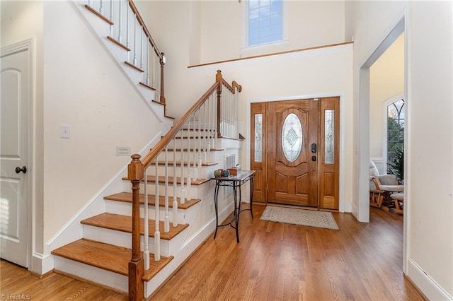 entrance foyer with light hardwood / wood-style floors and a towering ceiling