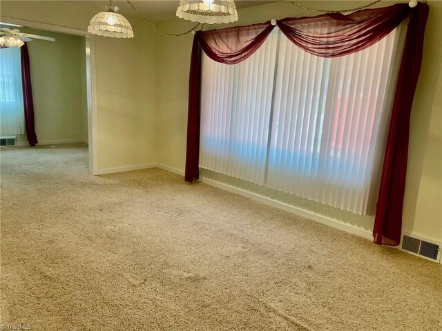 unfurnished room featuring carpet, visible vents, and baseboards