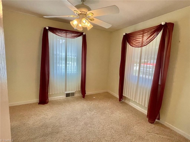 empty room with baseboards, visible vents, a ceiling fan, and light colored carpet