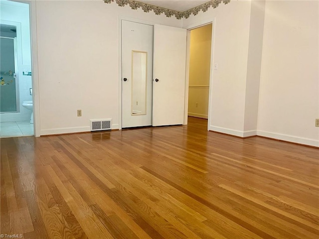 unfurnished room featuring baseboards, visible vents, and wood finished floors