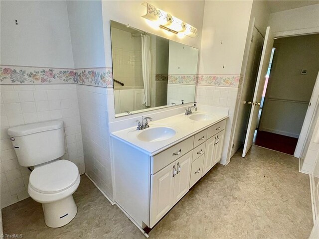 full bathroom featuring tile walls, a sink, and wainscoting