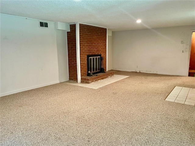 unfurnished living room with carpet floors, a fireplace, visible vents, a textured ceiling, and baseboards