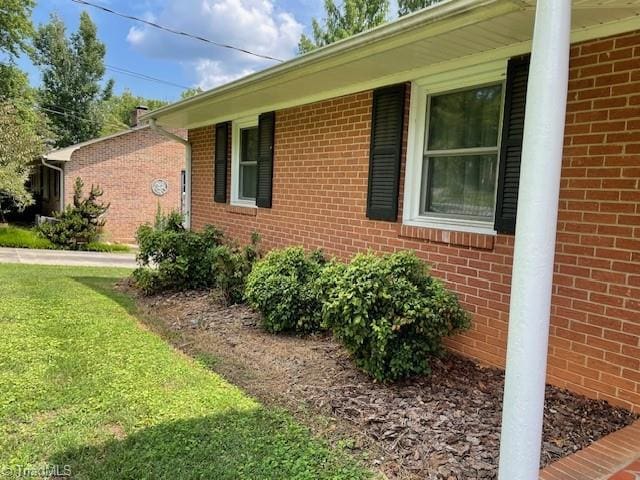 view of property exterior featuring brick siding and a lawn