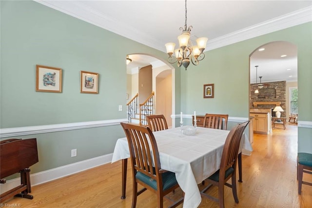 5584 Foxgate Cir, Winston-Salem, NC 27106 - dining room with arched walkways, light wood-style floors, a chandelier, crown molding, and baseboards