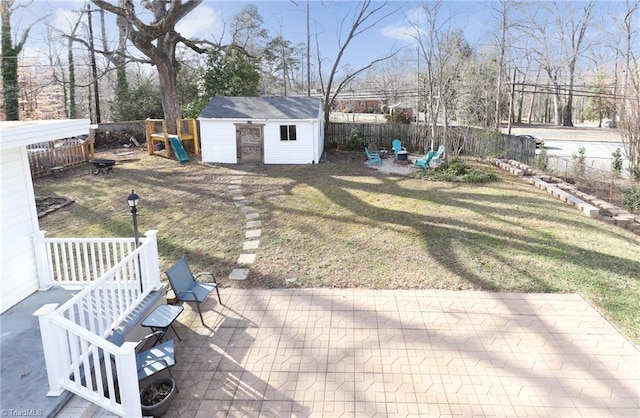 view of yard with a patio, an outdoor fire pit, an outdoor structure, and a fenced backyard