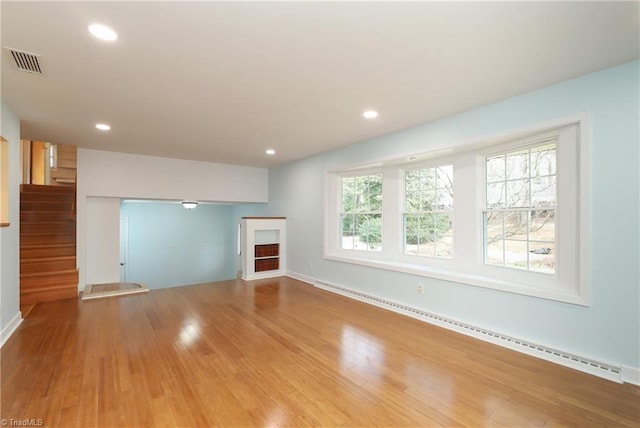 unfurnished living room featuring a baseboard radiator, recessed lighting, wood finished floors, visible vents, and stairway