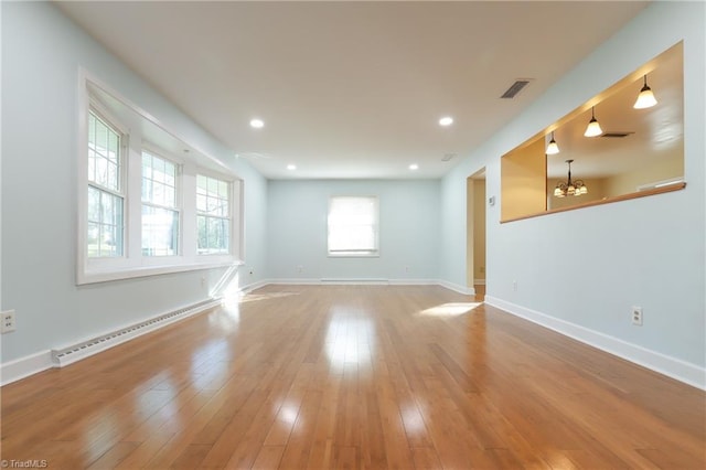 unfurnished room featuring light wood finished floors, baseboards, visible vents, and baseboard heating