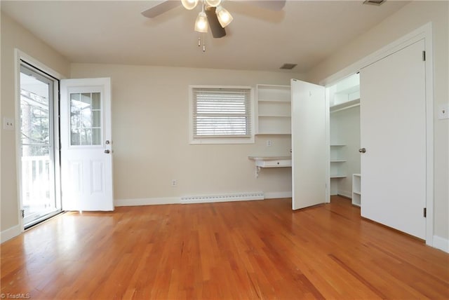 interior space featuring multiple windows, baseboard heating, light wood-type flooring, and visible vents