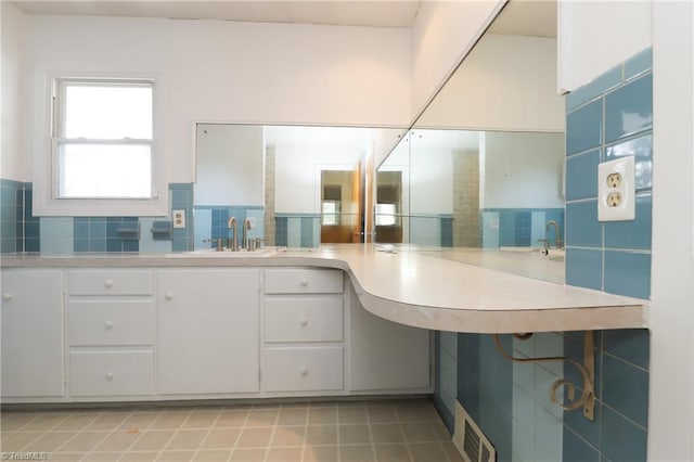 bathroom featuring backsplash, tile patterned flooring, a sink, and visible vents