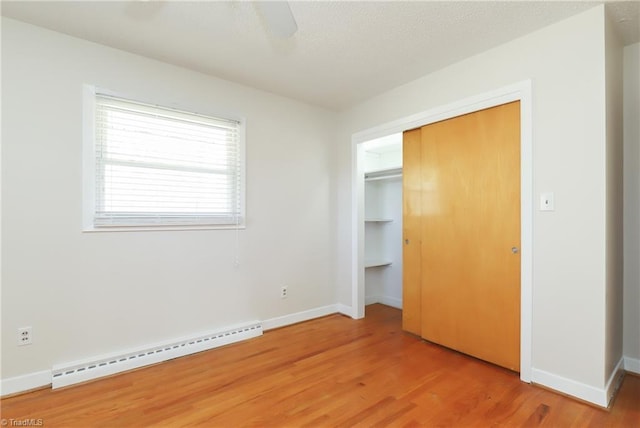 unfurnished bedroom with a baseboard heating unit, baseboards, ceiling fan, and light wood finished floors