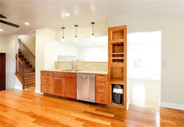 kitchen with a sink, light wood finished floors, brown cabinetry, and stainless steel dishwasher