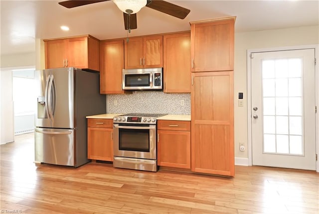 kitchen with stainless steel appliances, tasteful backsplash, light countertops, a ceiling fan, and light wood-type flooring