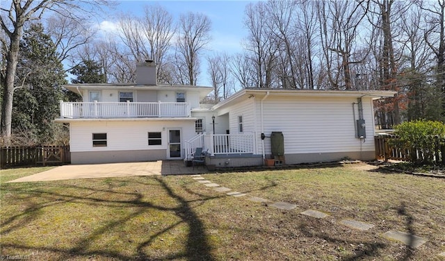 rear view of property featuring a patio, a chimney, a lawn, fence, and a balcony