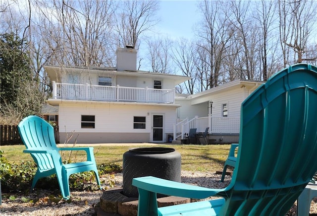 back of property with a lawn, a chimney, fence, and a balcony