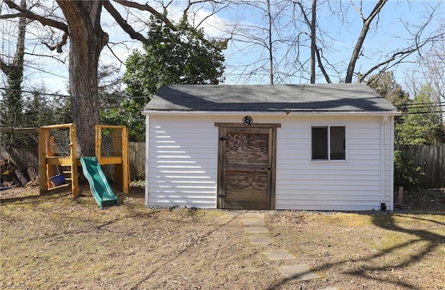 view of outbuilding featuring a playground, an outdoor structure, and fence