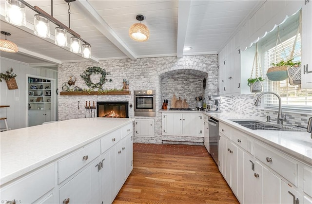 kitchen featuring white cabinetry, sink, stainless steel appliances, hanging light fixtures, and light hardwood / wood-style flooring