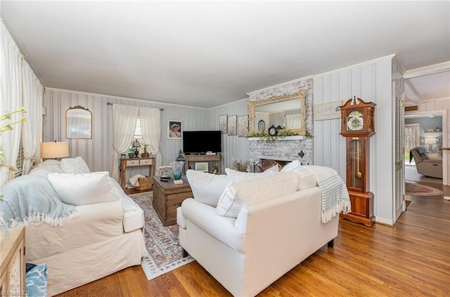 living room featuring a fireplace, hardwood / wood-style flooring, ornamental molding, and wood walls