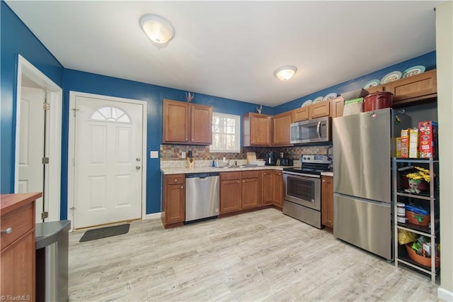 kitchen featuring appliances with stainless steel finishes, backsplash, light hardwood / wood-style floors, and sink